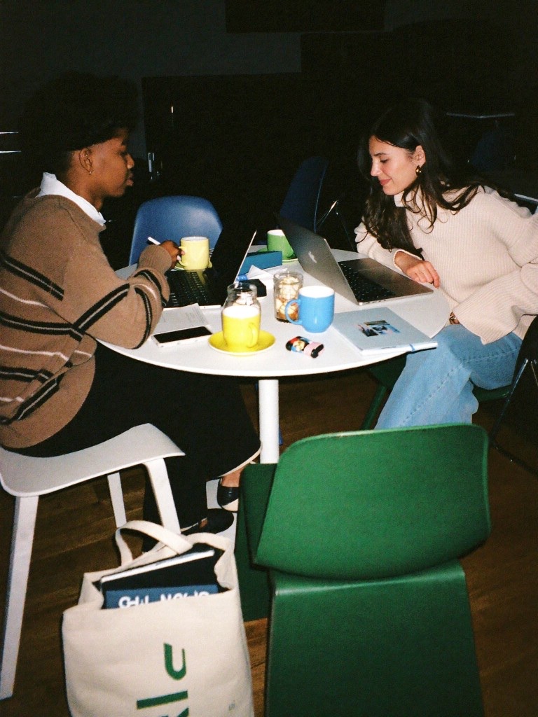 Two people working side by side at a café table with laptops and coffee