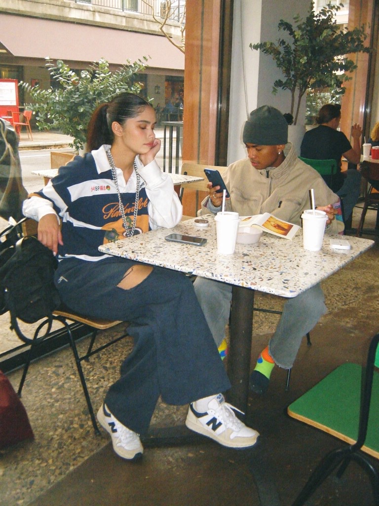 Two people sitting across from each other at a café table by a window